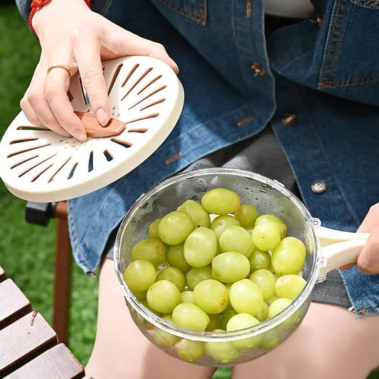 Person holding a glass bowl of green grapes with a plastic kitchen strainer lid, clarioy homeware.