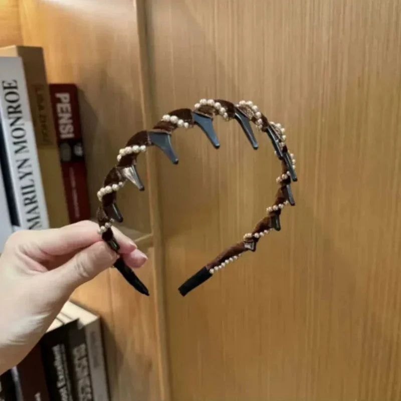 Hand holding brown pearl headband hair accessory with clips, bookshelf background, clarioy homeware.