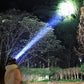 Person outdoors at night using powerful clarioy flashlight to illuminate trees in the dark.