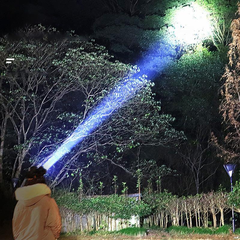 Person outdoors at night using powerful clarioy flashlight to illuminate trees in the dark.