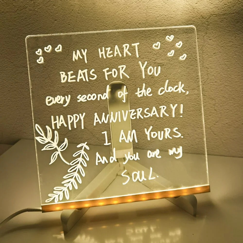 LED acrylic message board with handwritten anniversary quote, decorative leaves, and heart accents