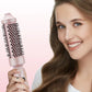 Woman smiling while holding a pink hair dryer brush, premium homeware from clarioy.