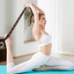 Woman in white activewear using stretch strap for yoga on blue mat in bright modern room