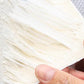 Close-up of a hand holding shredded white fiber material, homeware product at clarioy