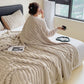 Woman relaxing on bed with soft beige chenille blanket, luxury homeware by clarioy