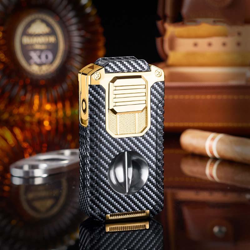 Luxury carbon fiber and gold torch cigar lighter with cigar, bottle, and case in background