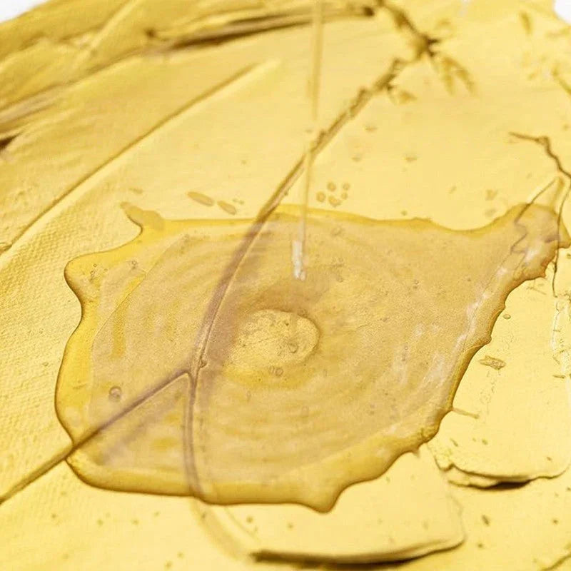 Close-up of clear golden liquid poured on textured yellow surface, premium homeware by clarioy