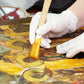 Gloved hands restoring artwork with a brush, premium homeware tool from clarioy