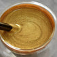 Gold metallic paint in a glass jar being mixed, premium homeware accessory from clarioy
